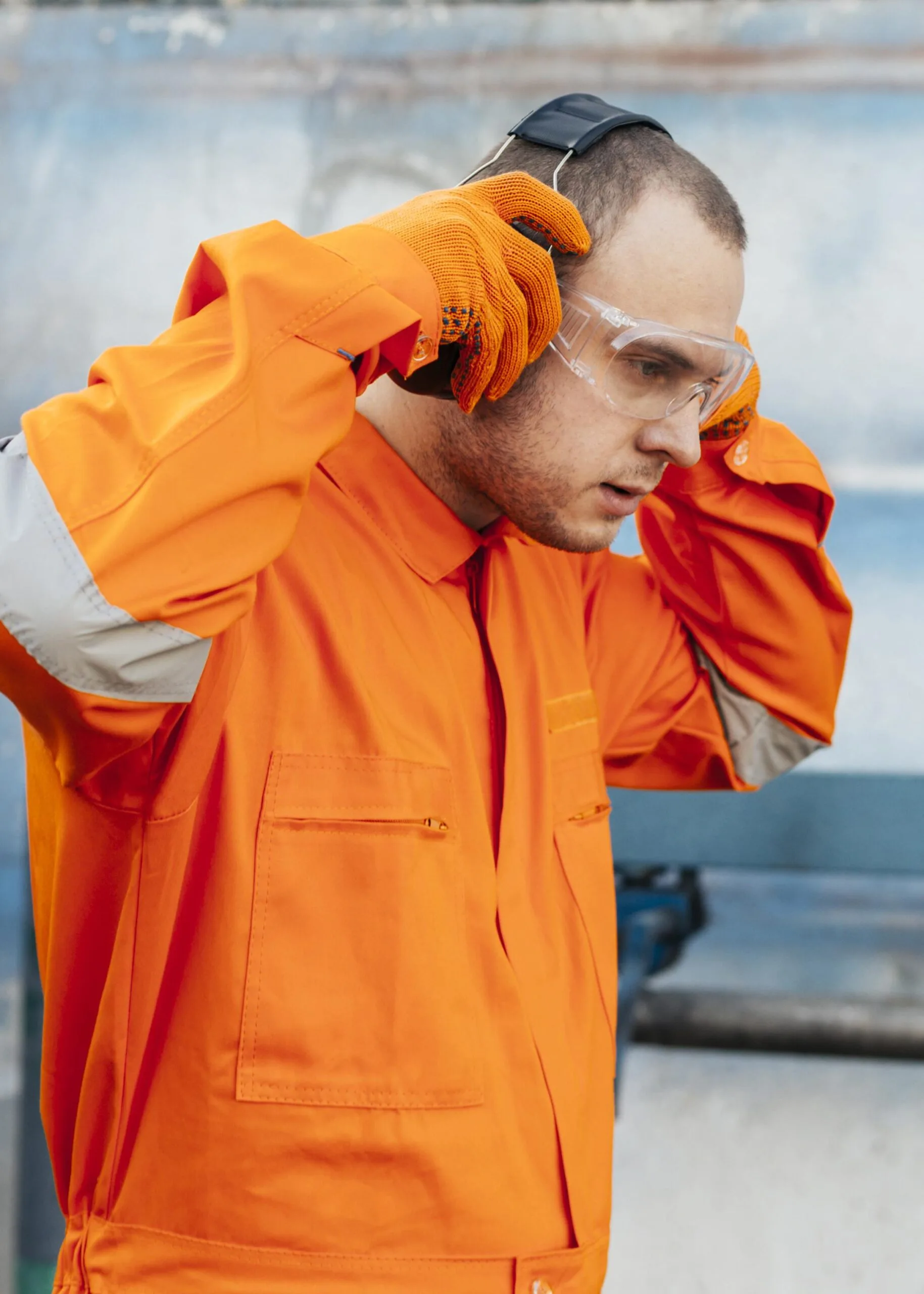 vue-laterale-du-travailleur-masculin-en-uniforme-avec-des-lunettes-de-protection-et-des-ecouteurs
